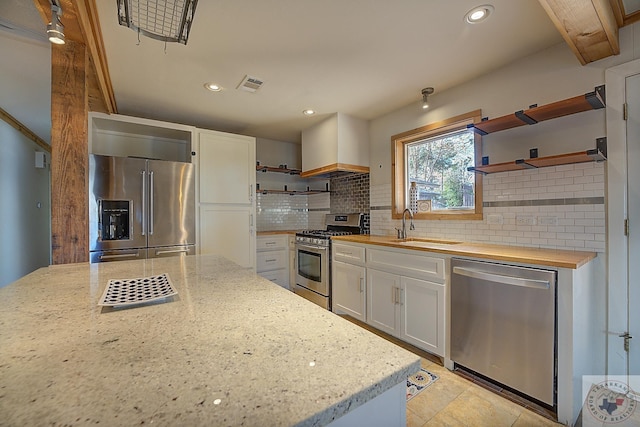 kitchen featuring sink, white cabinetry, light stone countertops, and appliances with stainless steel finishes