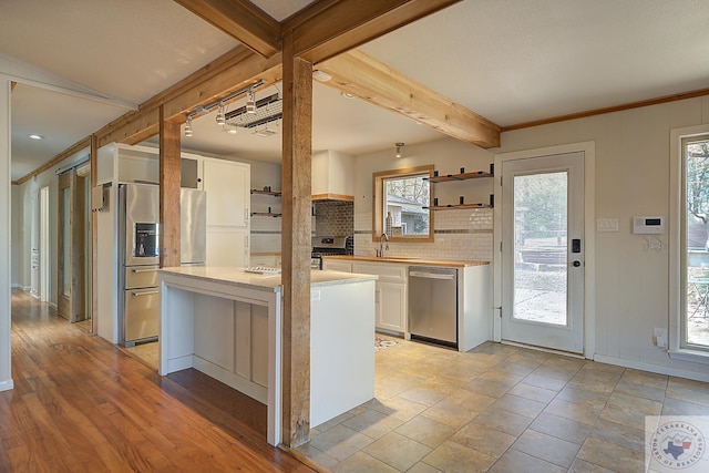 kitchen with appliances with stainless steel finishes, sink, backsplash, white cabinetry, and a kitchen island