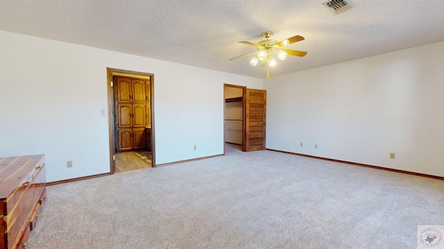 unfurnished bedroom with ceiling fan, light colored carpet, a spacious closet, connected bathroom, and a closet