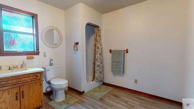 bathroom featuring curtained shower, hardwood / wood-style floors, a textured ceiling, vanity, and toilet