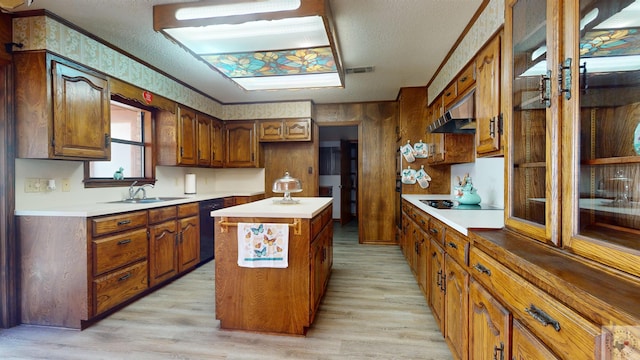 kitchen with sink, light hardwood / wood-style floors, a center island, a textured ceiling, and black appliances