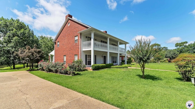 5906 Winchester Dr, Texarkana, TX 75503 - neoclassical home featuring a balcony, a chimney, brick siding, and a front yard