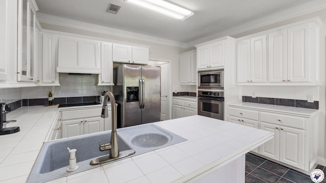 5906 Winchester Dr, Texarkana, TX 75503 - kitchen with appliances with stainless steel finishes, tile counters, white cabinetry, decorative backsplash, and crown molding