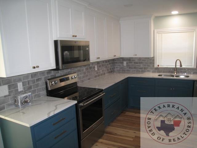 kitchen featuring sink, backsplash, white cabinetry, and appliances with stainless steel finishes