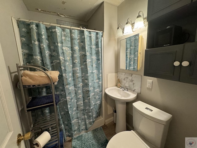 bathroom featuring sink, backsplash, toilet, and walk in shower