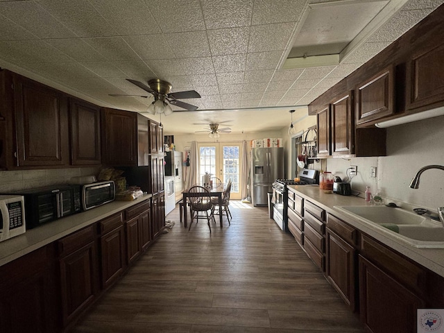 kitchen featuring dark brown cabinetry, dark wood-type flooring, stainless steel appliances, sink, and hanging light fixtures