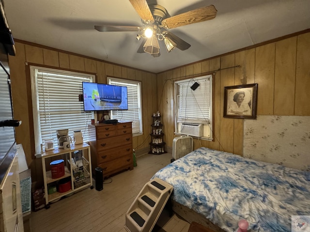 bedroom with ceiling fan, ornamental molding, and wood walls