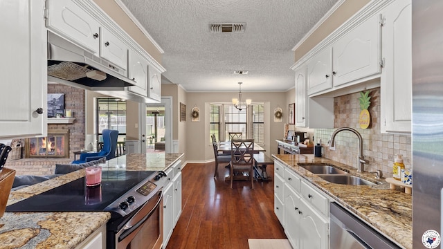 509 Brown Dr, Wake Village, TX 75501 - kitchen featuring appliances with stainless steel finishes, a textured ceiling, white cabinets, a fireplace, and backsplash