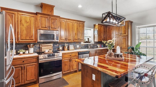 kitchen featuring tasteful backsplash, a breakfast bar area, appliances with stainless steel finishes, brown cabinets, and a sink