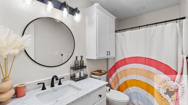 bathroom with curtained shower, vanity, and toilet