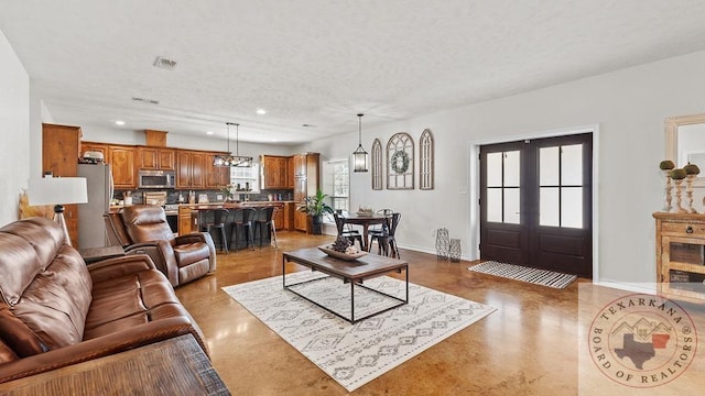 living area with baseboards, a textured ceiling, and french doors