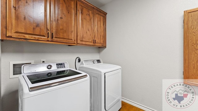 laundry room with washing machine and dryer, cabinet space, and baseboards