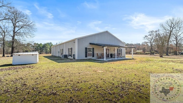 rear view of house with a lawn, an outdoor structure, cooling unit, and a patio