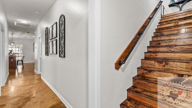 hallway featuring visible vents, concrete floors, stairway, and baseboards