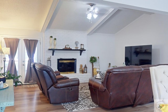 living room with ceiling fan, a brick fireplace, vaulted ceiling with beams, and light hardwood / wood-style floors