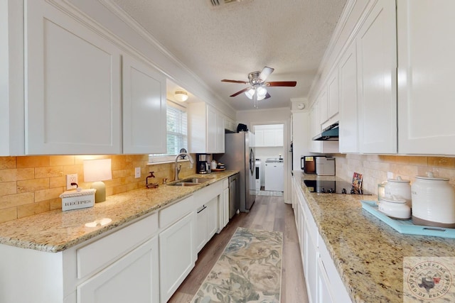 kitchen featuring sink, white cabinetry, backsplash, and washing machine and dryer