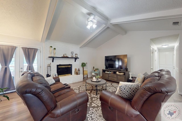 living room featuring a textured ceiling, hardwood / wood-style floors, lofted ceiling with beams, and a fireplace