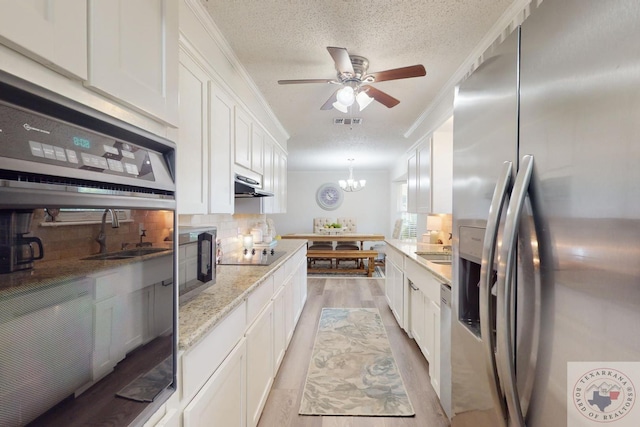 kitchen with white cabinets, black appliances, hanging light fixtures, light stone counters, and crown molding