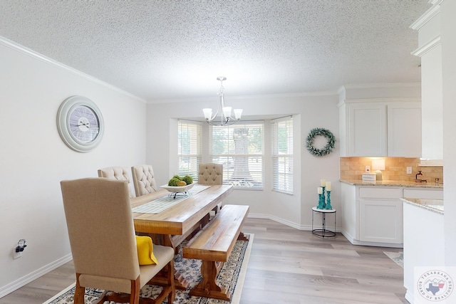 dining space with a textured ceiling, light hardwood / wood-style flooring, a notable chandelier, and ornamental molding