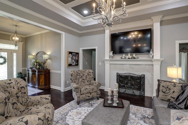 living room with dark wood-type flooring, a premium fireplace, crown molding, and a notable chandelier