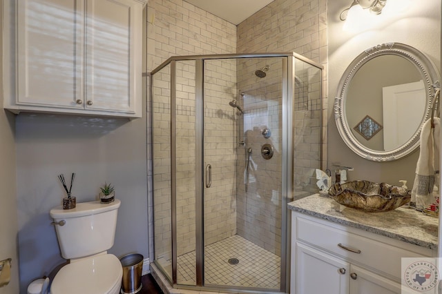 bathroom featuring toilet, vanity, and an enclosed shower