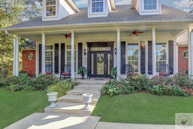 doorway to property with ceiling fan, a porch, and a yard