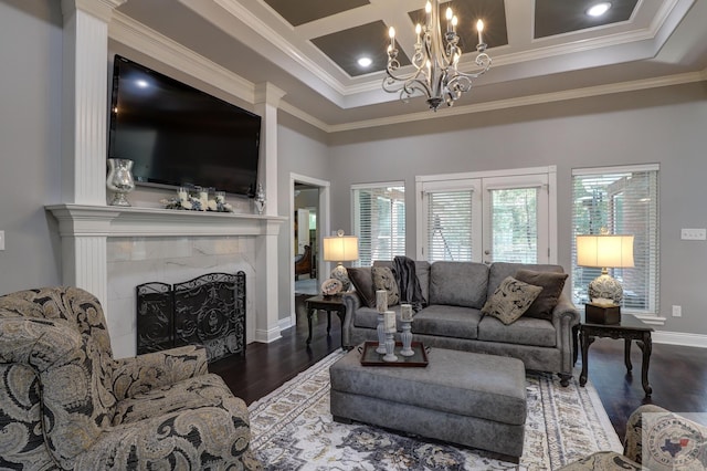 living room with crown molding, dark wood-type flooring, an inviting chandelier, and a premium fireplace