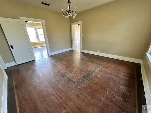 spare room with an inviting chandelier and dark hardwood / wood-style floors