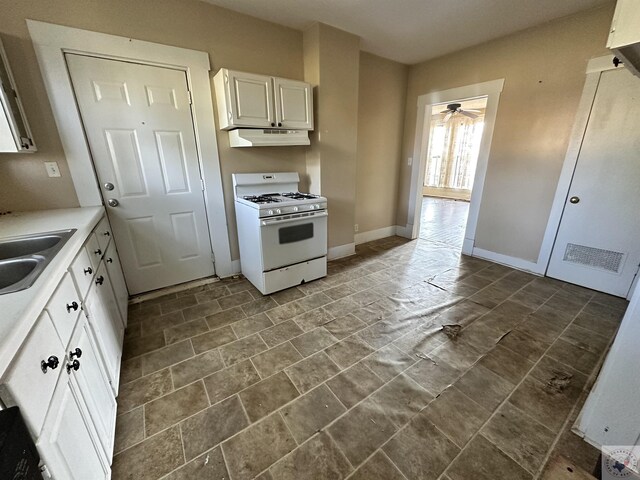 kitchen with ceiling fan, sink, white cabinets, and gas range gas stove