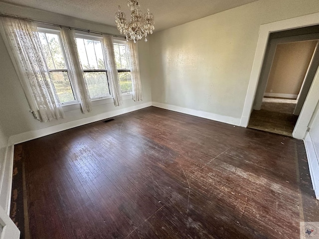 unfurnished dining area with a chandelier, dark wood-type flooring, and a textured ceiling