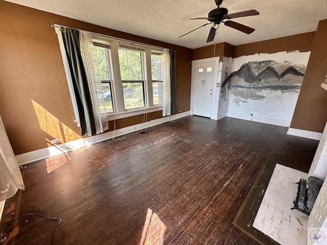 unfurnished living room featuring dark wood-type flooring, a textured ceiling, and ceiling fan