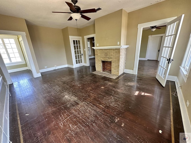 unfurnished living room featuring a fireplace, a textured ceiling, ceiling fan, and french doors