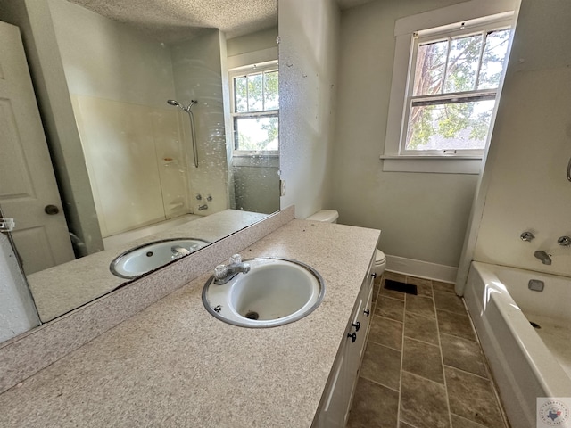 bathroom featuring a textured ceiling, toilet, a wealth of natural light, and vanity