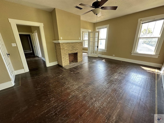 unfurnished living room featuring a textured ceiling, a fireplace, french doors, dark wood-type flooring, and ceiling fan