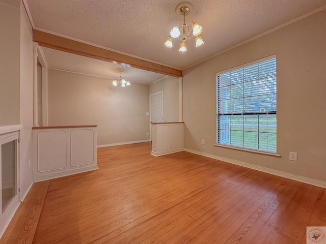 unfurnished living room with a textured ceiling, light hardwood / wood-style flooring, a notable chandelier, and ornamental molding