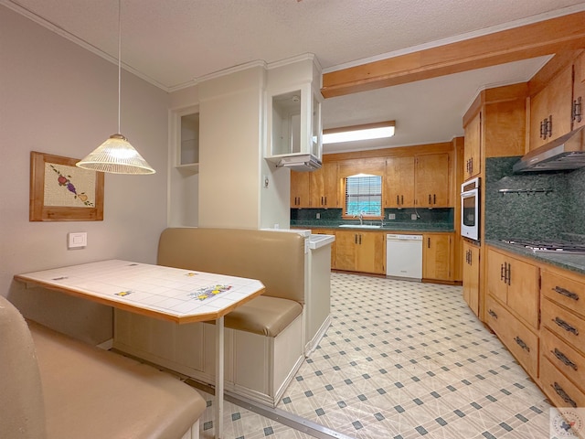 kitchen with crown molding, hanging light fixtures, appliances with stainless steel finishes, decorative backsplash, and tile counters