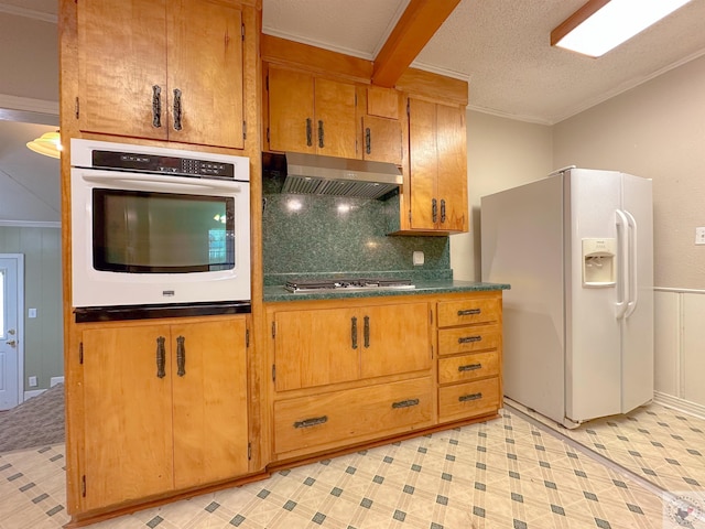 kitchen with crown molding, white appliances, a textured ceiling, wall chimney range hood, and beamed ceiling