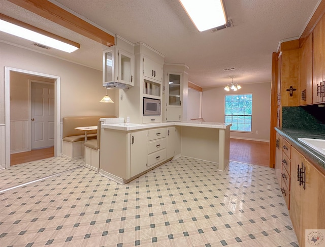 kitchen featuring stainless steel microwave, hanging light fixtures, sink, backsplash, and an inviting chandelier