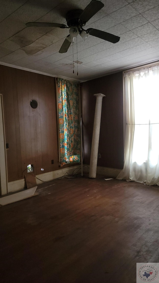 unfurnished room featuring ceiling fan and wood walls