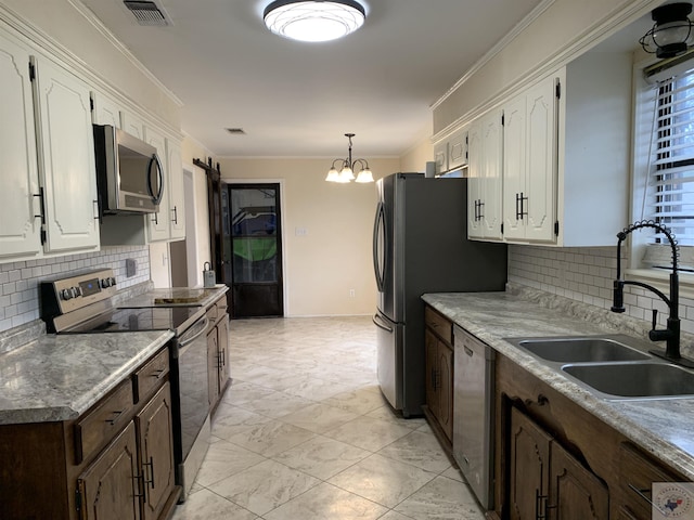 kitchen featuring white cabinets, ornamental molding, appliances with stainless steel finishes, and a sink