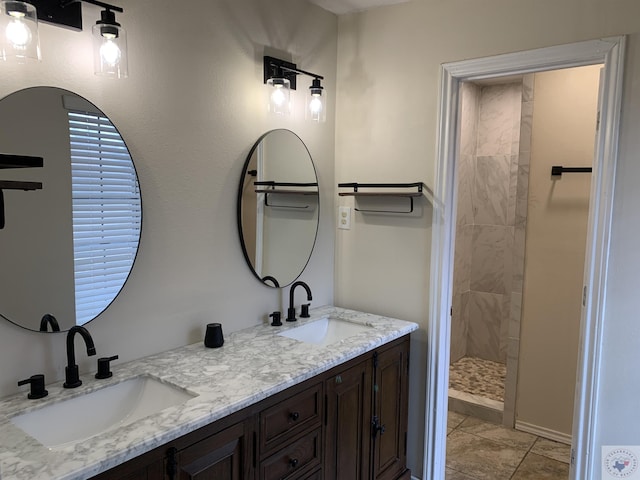 bathroom featuring double vanity, tile patterned floors, tiled shower, and a sink