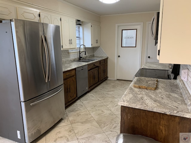 kitchen featuring ornamental molding, a sink, appliances with stainless steel finishes, white cabinetry, and tasteful backsplash