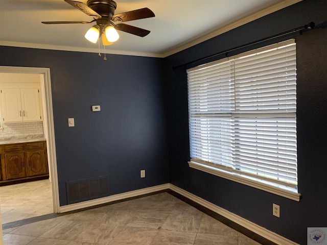 spare room featuring ceiling fan, visible vents, baseboards, and ornamental molding