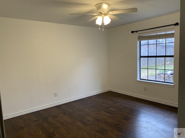 empty room with dark wood-style floors, a ceiling fan, and baseboards