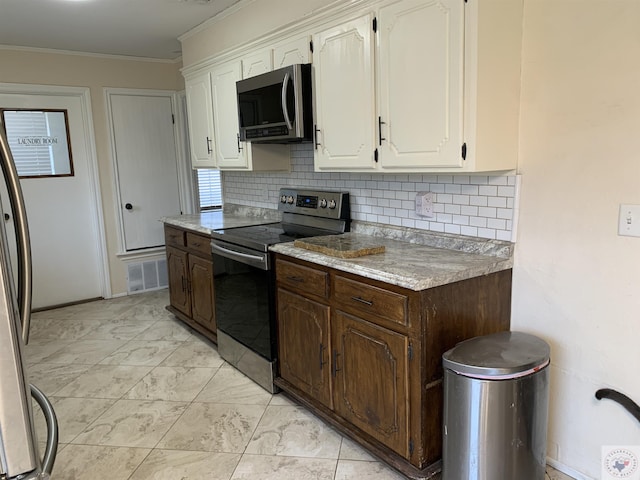 kitchen featuring visible vents, white cabinetry, stainless steel appliances, and ornamental molding