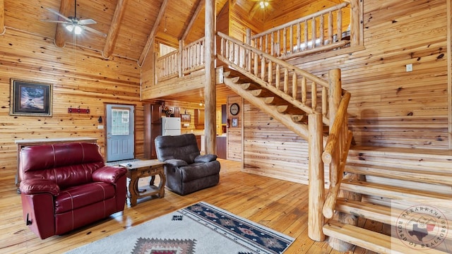 living area featuring wood walls, wood finished floors, wood ceiling, stairway, and beam ceiling