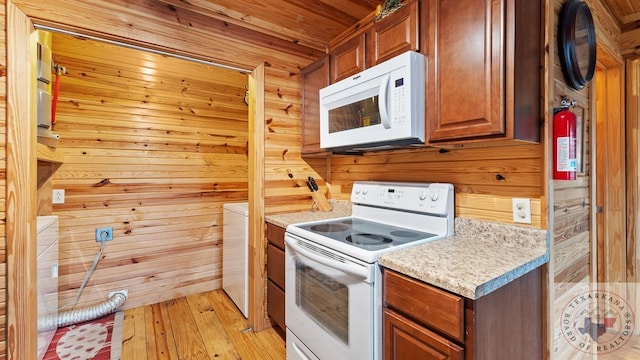 kitchen featuring white appliances, wood walls, wood ceiling, light countertops, and light wood finished floors