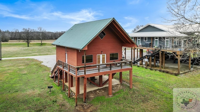 rear view of property featuring a yard, stairway, a wooden deck, faux log siding, and a patio area