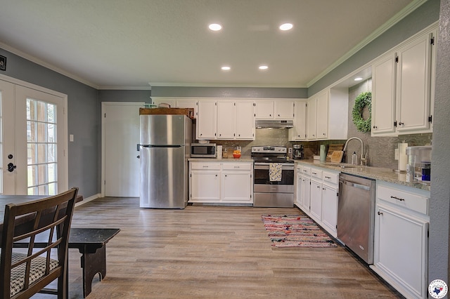 3009 Crestridge Dr, Texarkana, TX 75503 - kitchen featuring light wood finished floors, stainless steel appliances, a sink, white cabinetry, and under cabinet range hood