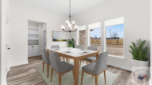 dining space featuring light wood-type flooring, a notable chandelier, and built in features